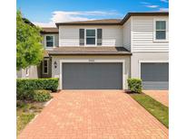 Two-story home featuring a brick driveway, gray two-car garage and well-maintained landscaping at 1045 Desert Candle Dr, Ocoee, FL 34761