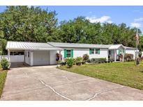 Charming single-story home featuring a driveway, metal roof and well-maintained lawn at 13009 Plum Lake Cir, Minneola, FL 34715