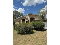 Beige one story home with mature shrubs in front yard under sunny skies at 13543 Emeraldview Dr, Orlando, FL 32828