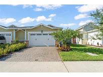 Charming home featuring a well-manicured lawn, brick driveway, and a two-car garage at 2301 Datura Loop, St Cloud, FL 34772