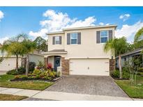 Charming two-story home featuring a stone facade, manicured landscaping, and a brick-paved driveway at 266 Caryota Ct, New Smyrna Beach, FL 32168