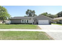 Charming single-story home with a well-manicured lawn and a gray exterior with stone accents at 347 Timberwood Trl, Oviedo, FL 32765