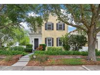 Charming two-story home featuring a balcony, black shutters, lush landscaping, and mature trees in a desirable neighborhood at 4001 Corrine Dr, Orlando, FL 32814