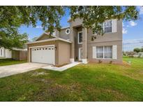 Charming two-story home with a lush green lawn and an attached two-car garage at 401 Magpie Ct, Kissimmee, FL 34759