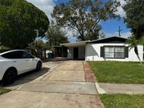 Charming single-story home with a long driveway and a modern white car parked in front at 4061 Kirkland Blvd, Orlando, FL 32811