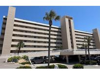 Beachside condo building featuring a parking garage, palm trees, and multiple balconies at 4453 S Atlantic Ave # 602, Ponce Inlet, FL 32127
