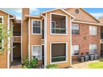 View of the exterior elevation of the building with a combination of wood and brick, and a few windows at 5540 Devonbriar Way # 103, Orlando, FL 32822