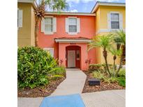 Brightly painted townhome with well-manicured landscaping and a clear, inviting walkway leading to the front door at 8502 Crystal Cove Loop, Kissimmee, FL 34747