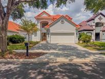 Charming two-story home featuring a red tile roof, a brick driveway and lush landscaping at 8515 Saint Marino Blvd, Orlando, FL 32836
