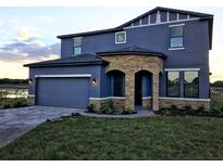 Charming two-story home features a stone-accented entry, attached garage, and well-maintained landscaping at 9208 Chandler Dr, Groveland, FL 34736