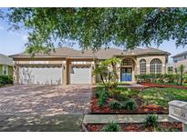 Charming single-Gathering home showcasing a well-manicured front yard, brick driveway, and a three-car garage at 10030 Chatham Oaks Ct, Orlando, FL 32836