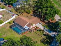 Aerial view of a home with a screened-in pool, landscaping, long driveway, and mature trees at 10545 Parkway Dr, Clermont, FL 34711
