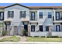 Modern townhome exterior with neutral paint, black iron gates, and well maintained front lawn and professional landscaping at 123 Kenny Blvd, Haines City, FL 33844