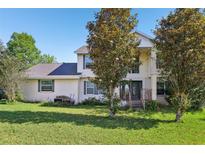 Two-story home with a well-manicured lawn and mature trees in front at 16249 Se 162Nd Ct, Weirsdale, FL 32195