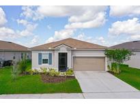 Charming single-story home featuring a well-manicured lawn, a two car garage, and beautiful landscaping at 200 Summershore Dr, Auburndale, FL 33823