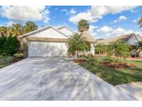 Charming one-story home featuring a two-car garage and lush landscaping with young palm trees at 25 Reflections Village Dr, Ormond Beach, FL 32174