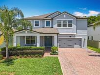 Charming two-story home featuring a well-manicured lawn and a brick driveway leading to a two-car garage at 2676 Estuary Loop, Oviedo, FL 32765