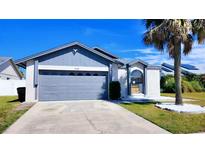 Charming single-Gathering home featuring a gray two-car garage and a well-manicured lawn at 3129 Arrow Dr, Kissimmee, FL 34746