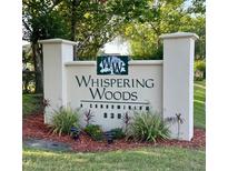 Welcoming sign for Whispering Woods Condominiums with attractive landscaping and well-maintained surroundings at 830 Airport Rd # 115, Port Orange, FL 32128