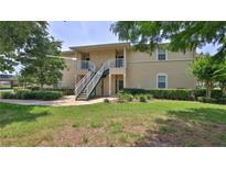 Inviting two-story condo with lush landscaping and stairs leading to the second level at 830 Airport Rd # 115, Port Orange, FL 32128