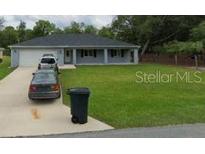 Charming single-story home with a columned front porch and a well-manicured front lawn at 9338 Se 157Th Pl, Summerfield, FL 34491