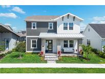 Charming two-story home with a cozy front porch swing, lush lawn and vibrant landscaping on a sunny day at 10183 Peebles St, Orlando, FL 32827