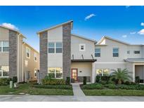 Modern two-story home with stone accents, manicured landscaping, and a vibrant red front door at 1128 Challenge Dr, Davenport, FL 33896
