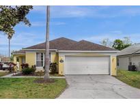 Charming yellow home featuring a two-car garage, well-maintained lawn, and inviting curb appeal at 217 Holborn Loop, Davenport, FL 33897