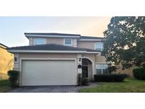 Charming two-story home with brick driveway, well-manicured lawn, and an attached two-car garage at 225 Vista Dr, Davenport, FL 33897