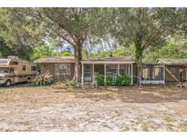 Charming single-story home featuring a cozy front porch nestled among mature trees and landscaping at 24089 Ne 152Nd Ln, Fort Mc Coy, FL 32134