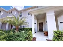 Inviting front entrance with well-maintained landscaping, brown door, and decorative wall art at 3083 Tom Sawyer Dr, Kissimmee, FL 34746