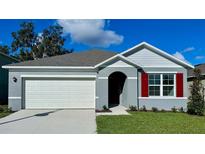 Charming single-story home with a two-car garage, gray stucco siding, red shutters, and a well-manicured lawn at 3418 Wynwood Forest Dr, Ocoee, FL 34761