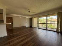 Bright living room with hardwood floors, ceiling fans, and sliding glass doors to a balcony at 592 Orange Dr # 142, Altamonte Springs, FL 32701