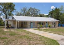 Charming single-story home featuring a metal roof, pale yellow exterior and a long driveway at 88 E Charlotte Ave, Eustis, FL 32726