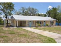 Inviting single-story home featuring a metal roof, covered front porch, and charming blue doors at 88 E Charlotte Ave, Eustis, FL 32726