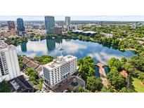 Stunning aerial view of a luxury building overlooking a scenic lake with a beautiful skyline backdrop at 100 S Eola Dr # 1406, Orlando, FL 32801