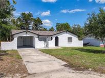Charming stucco home with a driveway, well-maintained lawn, and an attached carport at 1113 Leeward Dr, Deltona, FL 32738