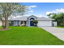 Charming single-story home featuring lush green lawn, arched entry, and attached two car garage at 1195 Tivoli Dr, Deltona, FL 32725