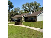 Charming one-story home featuring brick accents, lush landscaping, and mature trees, creating a welcoming curb appeal at 1219 Serissa Ct, Orlando, FL 32818