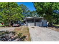 Charming single-story home featuring a covered parking area and mature trees on a sunny day at 2304 N Hastings St, Orlando, FL 32808
