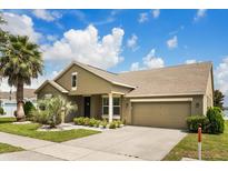 Inviting single-Gathering home featuring lush landscaping, a well-maintained lawn, and a two-car garage at 259 Blue Cypress Dr, Groveland, FL 34736
