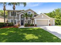 Inviting two-story home with a three-car garage, lush lawn, and elegant landscaping at 2607 Stanmore Ct, Orlando, FL 32817