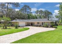 Charming ranch-style home with brick circular drive, lush lawn, mature trees and stone accents at 303 S Sweetwater Blvd, Longwood, FL 32779