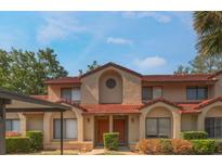 Two-story townhome with stucco facade, red tile roof, and landscaped front with covered parking at 424 Club Dr, Winter Springs, FL 32708