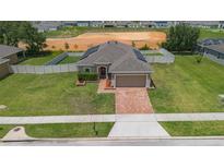 Charming single-story home with a well-manicured lawn, brick driveway, and neutral tones offers great curb appeal at 5515 Windsong Oak Dr, Leesburg, FL 34748