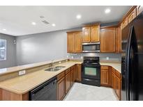 Well-lit kitchen features wood cabinets, granite counters, black appliances, and double bowl sink at 585 Cruz Bay Cir, Winter Springs, FL 32708
