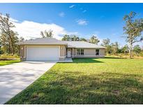 Charming single-story home with a two-car garage, lush lawn, and inviting curb appeal at 74 Malauka Pass, Ocklawaha, FL 32179