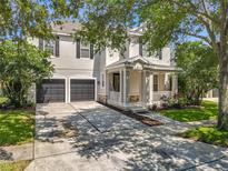 Charming two-story home featuring a welcoming front porch, dark shutters, and a spacious driveway and two-car garage at 9942 Sweetleaf St, Orlando, FL 32827