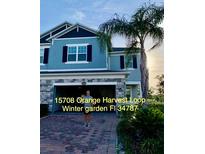 Two story home with light blue facade, brick driveway, and integrated two car garage and well landscaped front yard at 15708 Orange Harvest Loop, Winter Garden, FL 34787