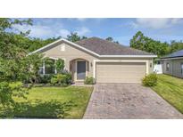 Charming single-story home with lush landscaping and a brick-paved driveway at 2426 Addison Creek Dr, Kissimmee, FL 34758